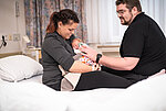 Ein Paar sitzt mit seinem Neugeborenen auf einem Bett in der Frauenklinik des St. Josefs-Hospitals Lennestadt. 