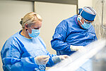 Ein Arzt und eine Ärztin untersuchen einen Patienten mit einem Herzkatheter.